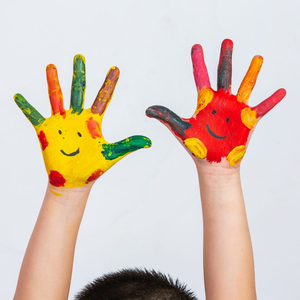 Mani colorate di un bambino con disegnati dei sorrisi